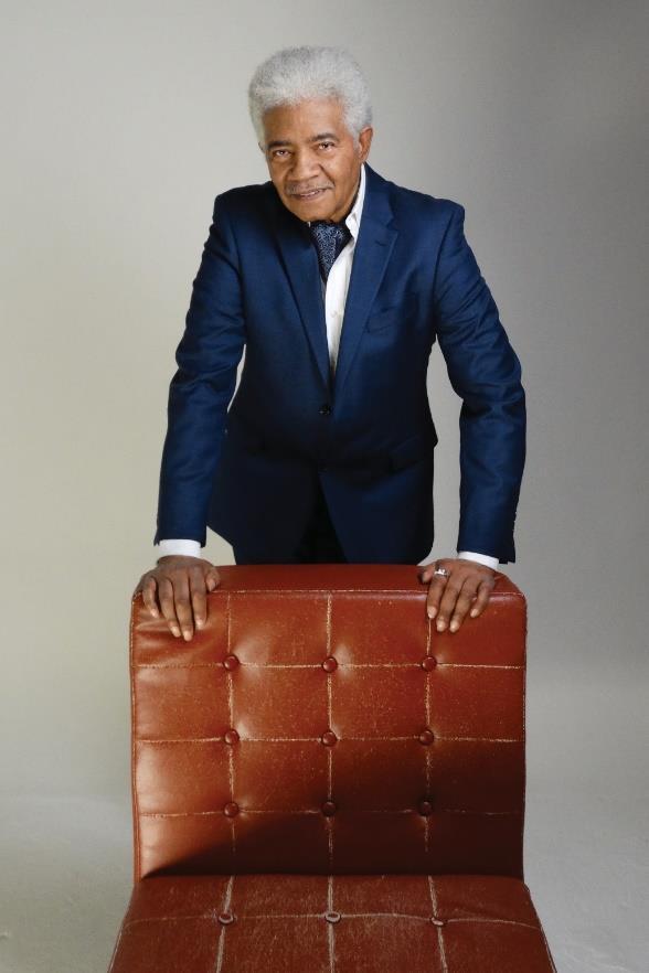 Melvin Moy standing behind a red studio chair