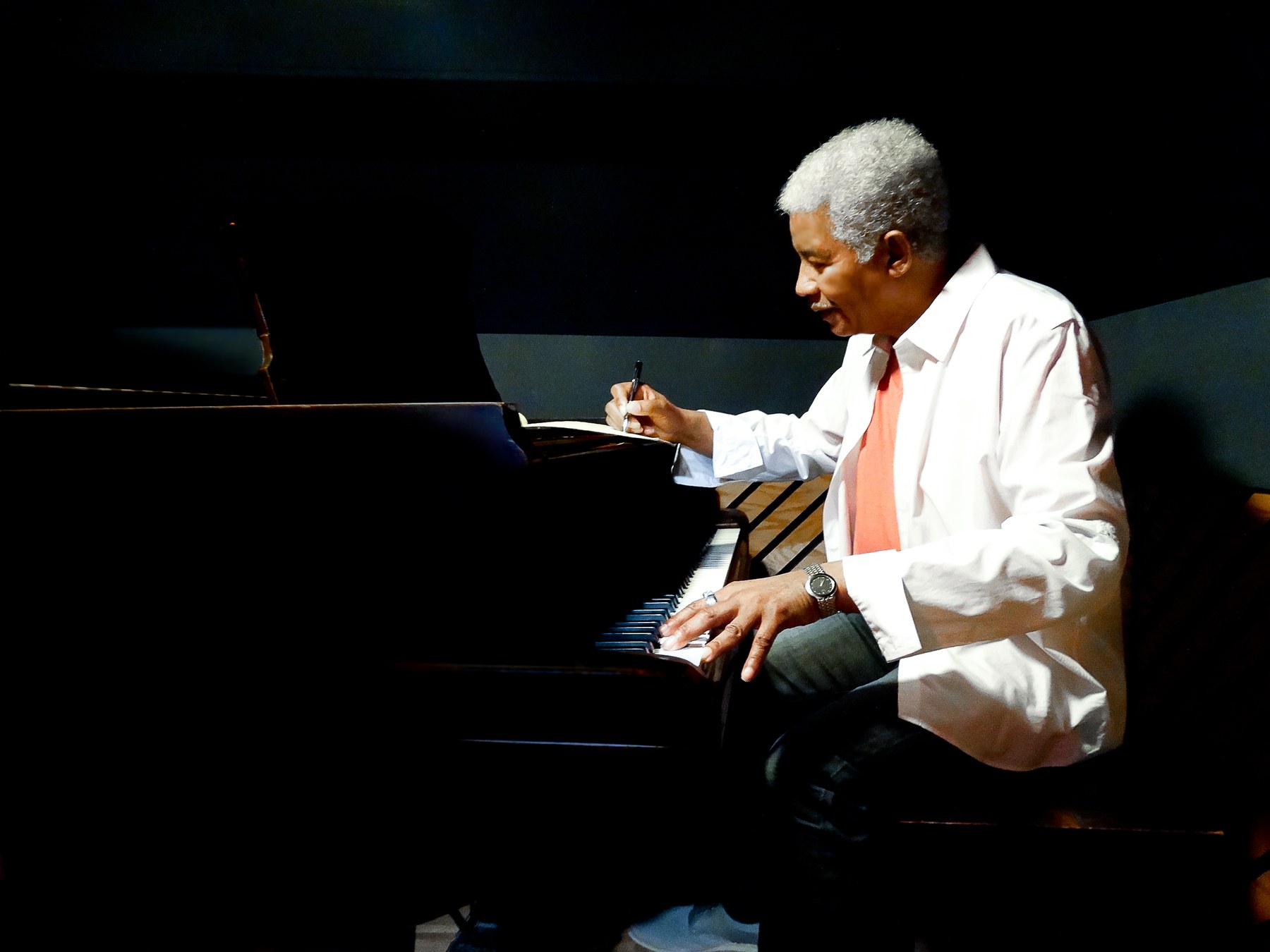 Melvin Moy writing at a piano