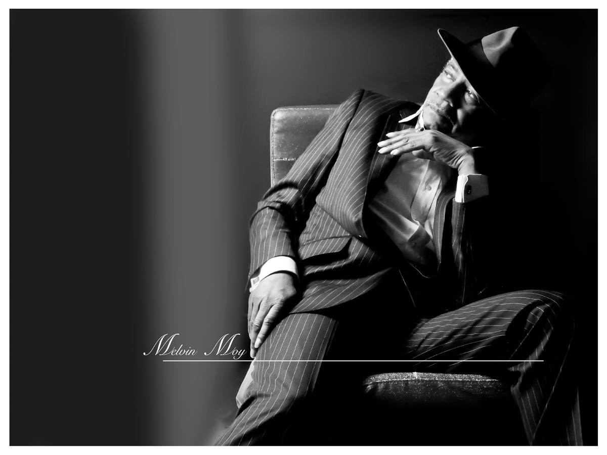 Black and white portrait of Melvin Moy in a pinstripe suit